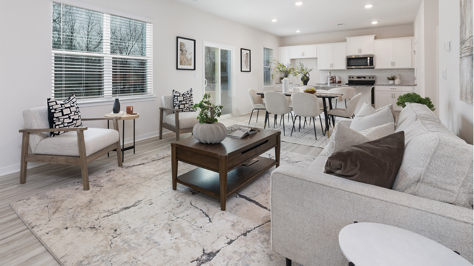 Open great room  beside kitchen, against staircase, with large window