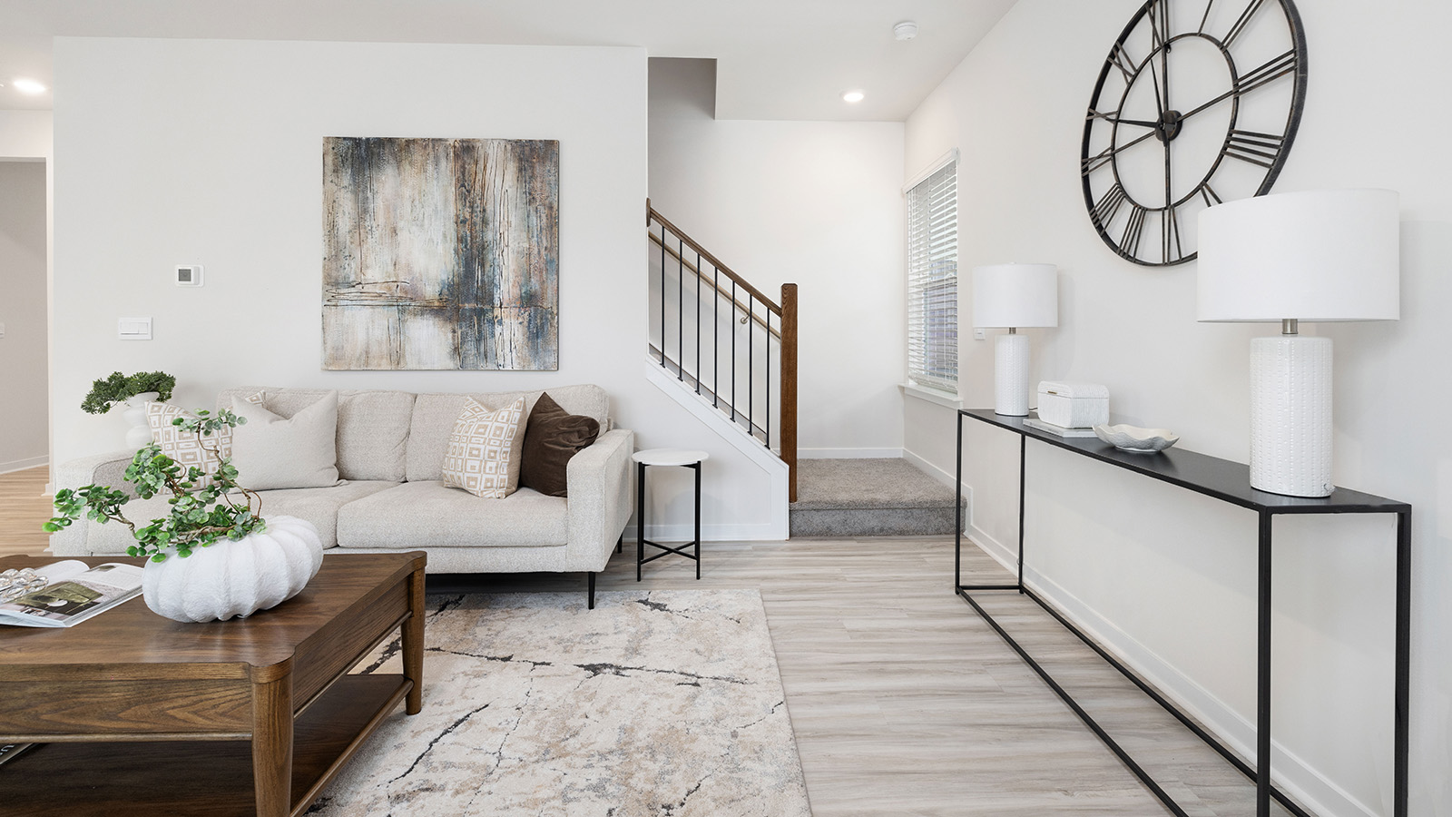 Open great room  beside kitchen, against staircase, with large window