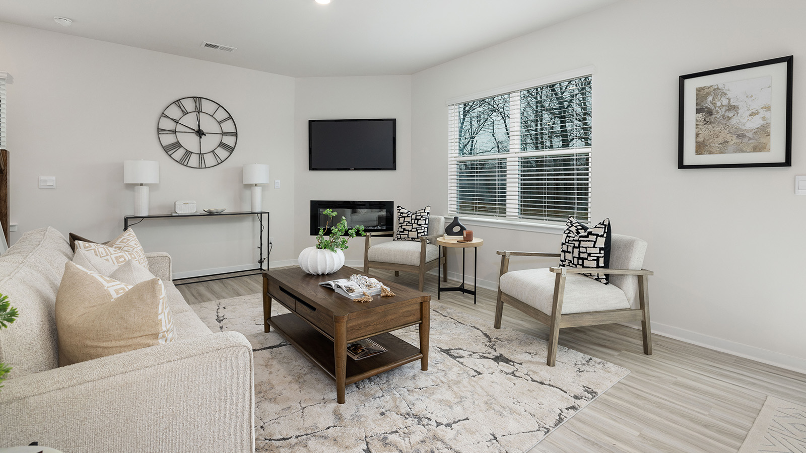 Open great room  beside kitchen, against staircase, with large window