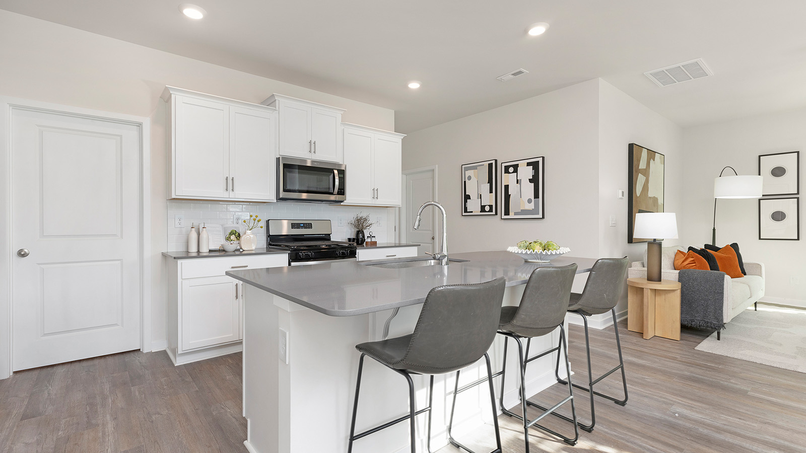 Kitchen and island with grey cabinets, subway tile backsplash, and stainless steel appliances