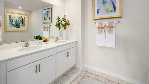 Primary bathroom with double sinks, white cabinets and counters
