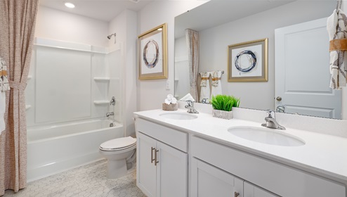 Bathroom with bathtub, double sinks, and white counters and cabinets