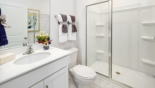 Bathroom with standing shower, white counter and cabinets