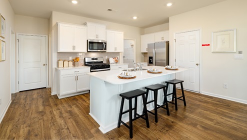 Kitchen and island with white cabinets and wood flooring