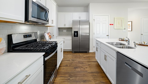 Kitchen and island with white cabinets and wood flooring
