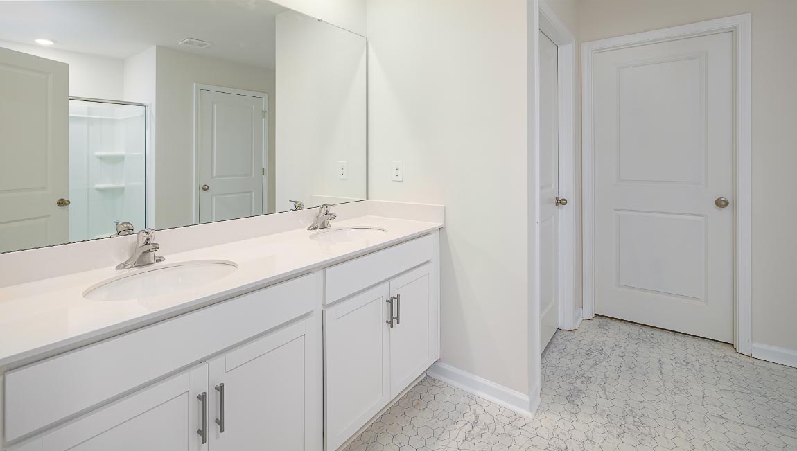 Primary bathroom with double sinks, white cabinets and counters