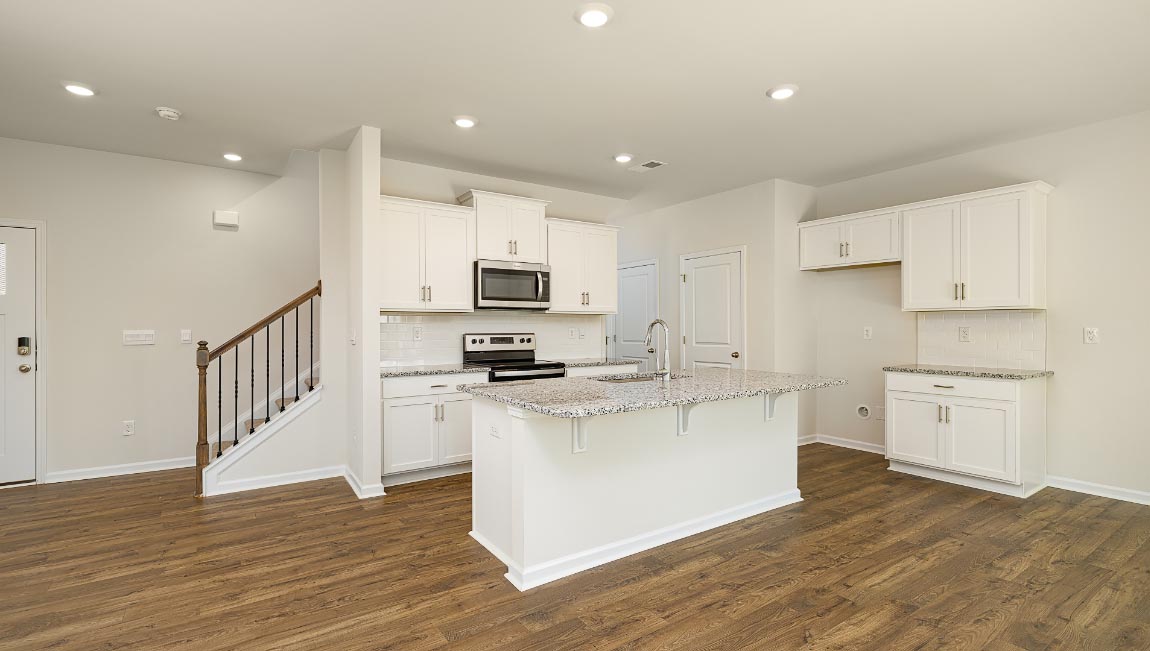 Kitchen and island, white cabinets, wood floors, and stainless steel appliances