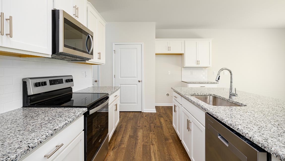 Kitchen and island, white cabinets, wood floors, and stainless steel appliances