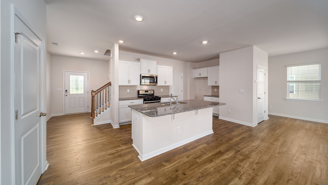 Kitchen and island with white cabinets, white subway tile backsplash and stainless steel appliances