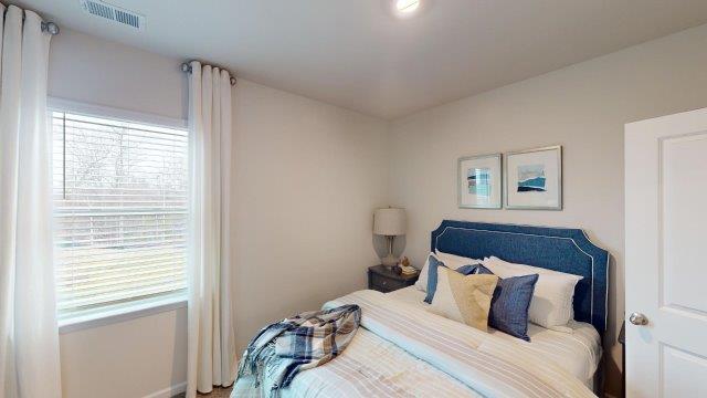 Bedroom featuring a bed, decorated in dark blue tones with a large window