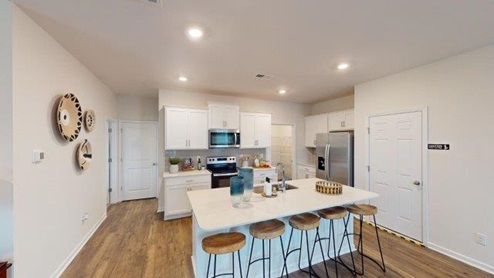 Kitchen and island with white cabinets and counters, and stainless steel appliances