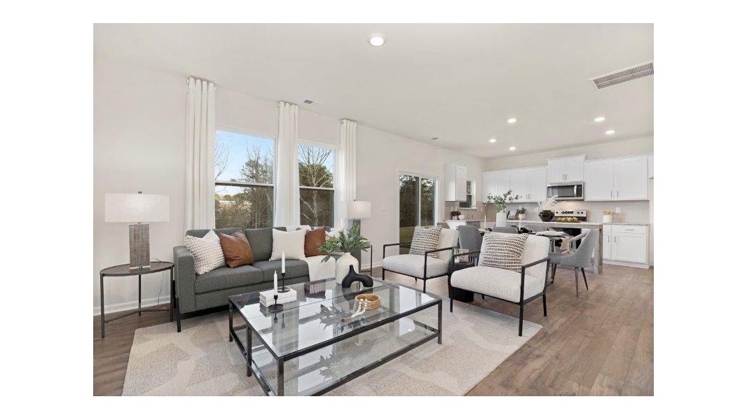 Open living room by kitchen with electric fireplace and large windows