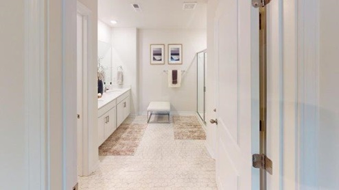 Primary bathroom with white cabinets and counters, and glass door shower