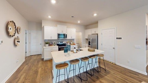 Kitchen and island with white cabinets and counters, and stainless steel appliances