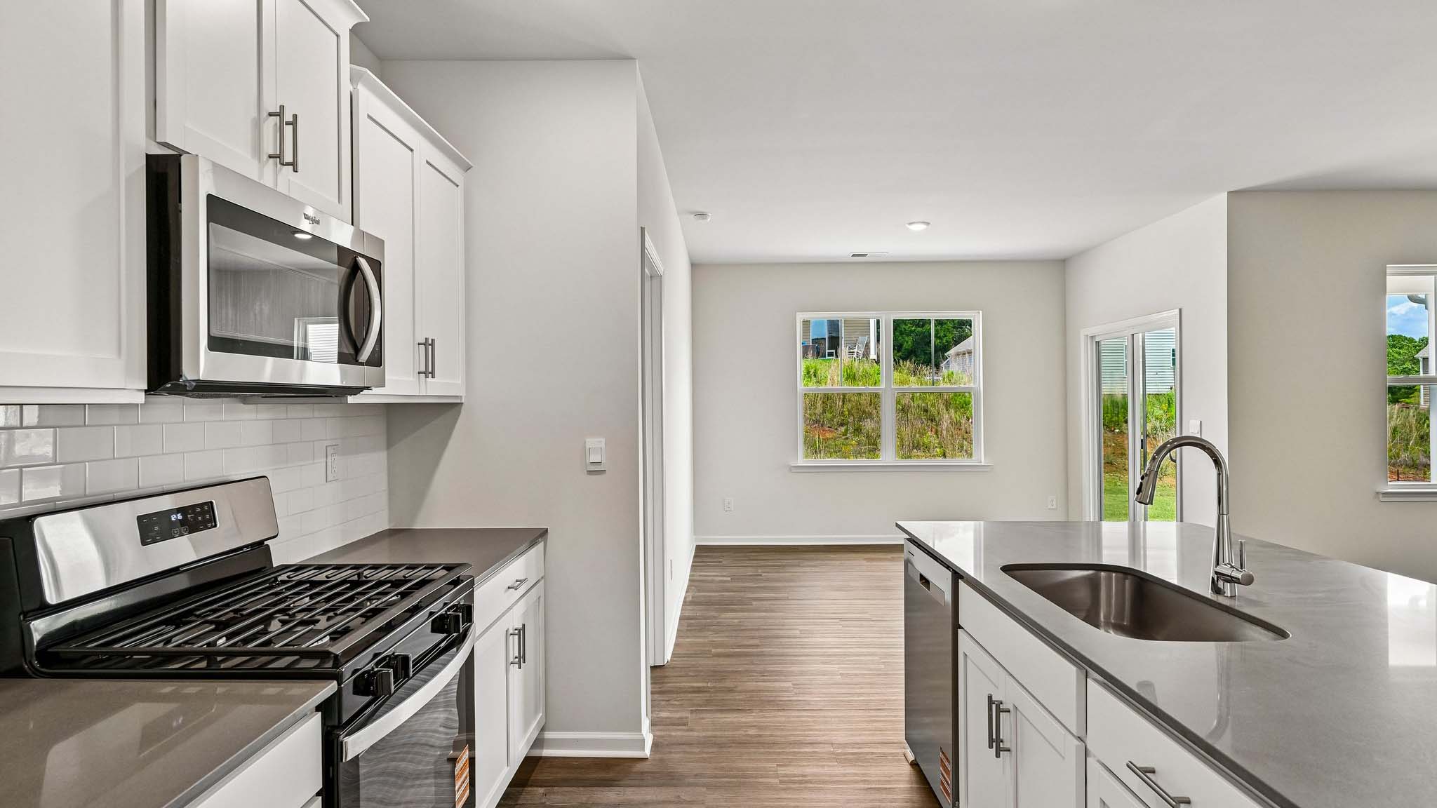 Kitchen and island with white cabinets, quarts countertops, wood floors, and stainless steel appliances