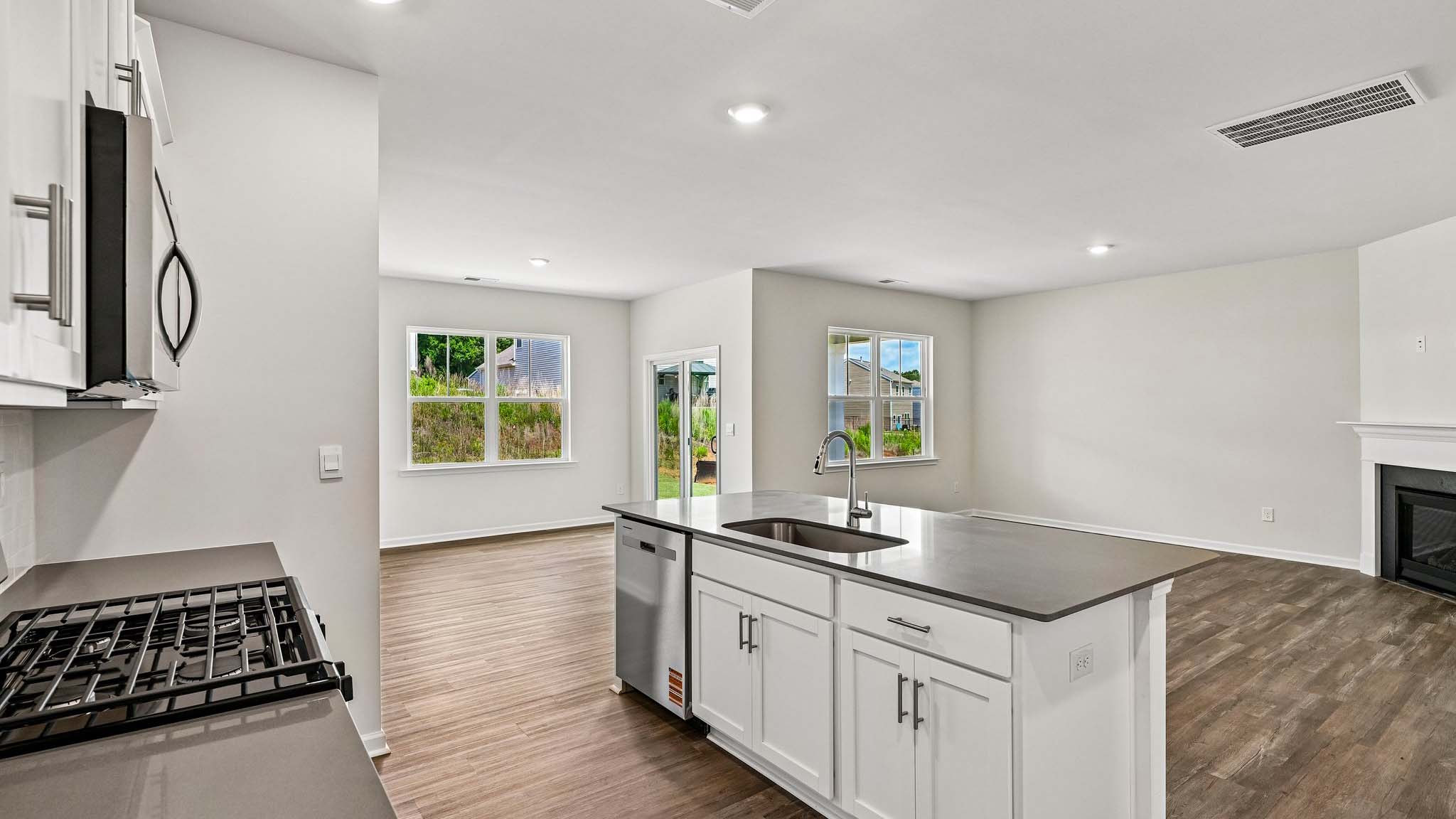 Kitchen and island with white cabinets, quarts countertops, wood floors, and stainless steel appliances