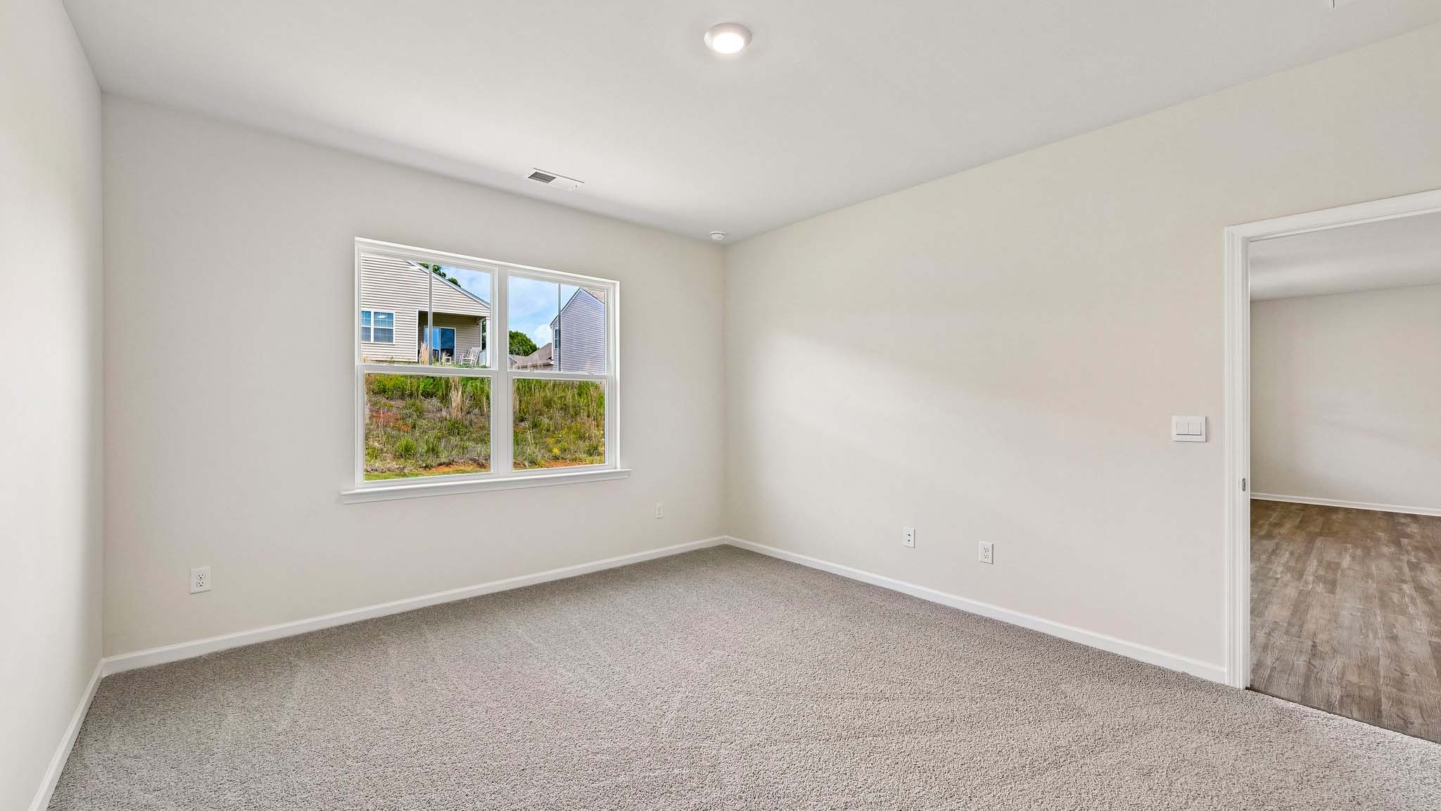 Primary carpeted bedroom with windows