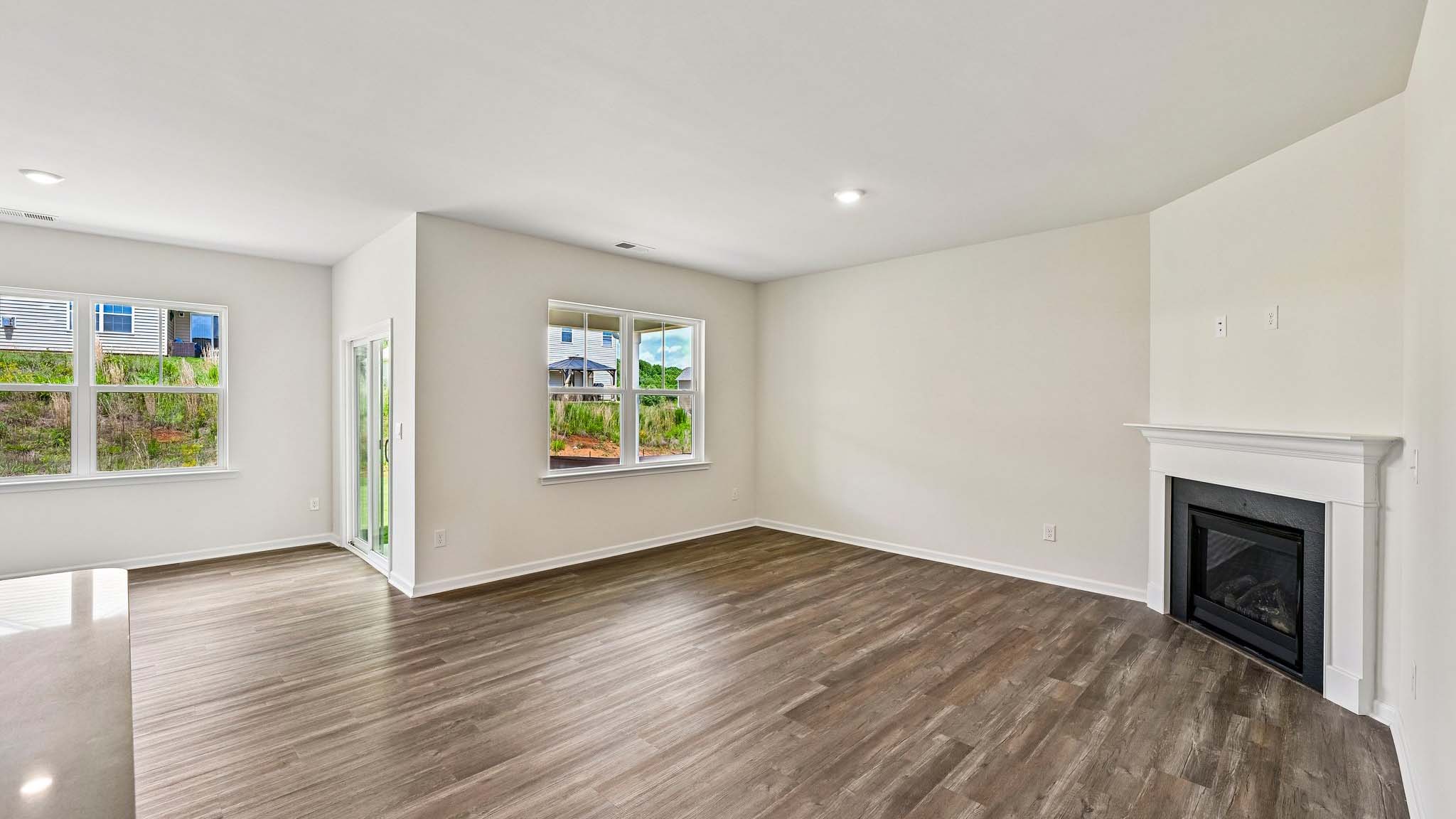 Modern open-concept living room with wood floors, and a fireplace, located beside kitchen