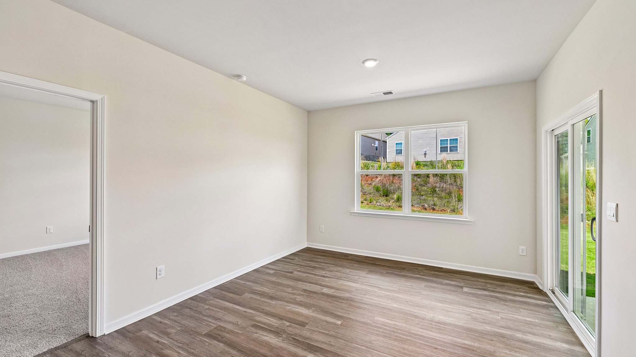 Modern open-concept living room with wood floors, and a fireplace, located beside kitchen