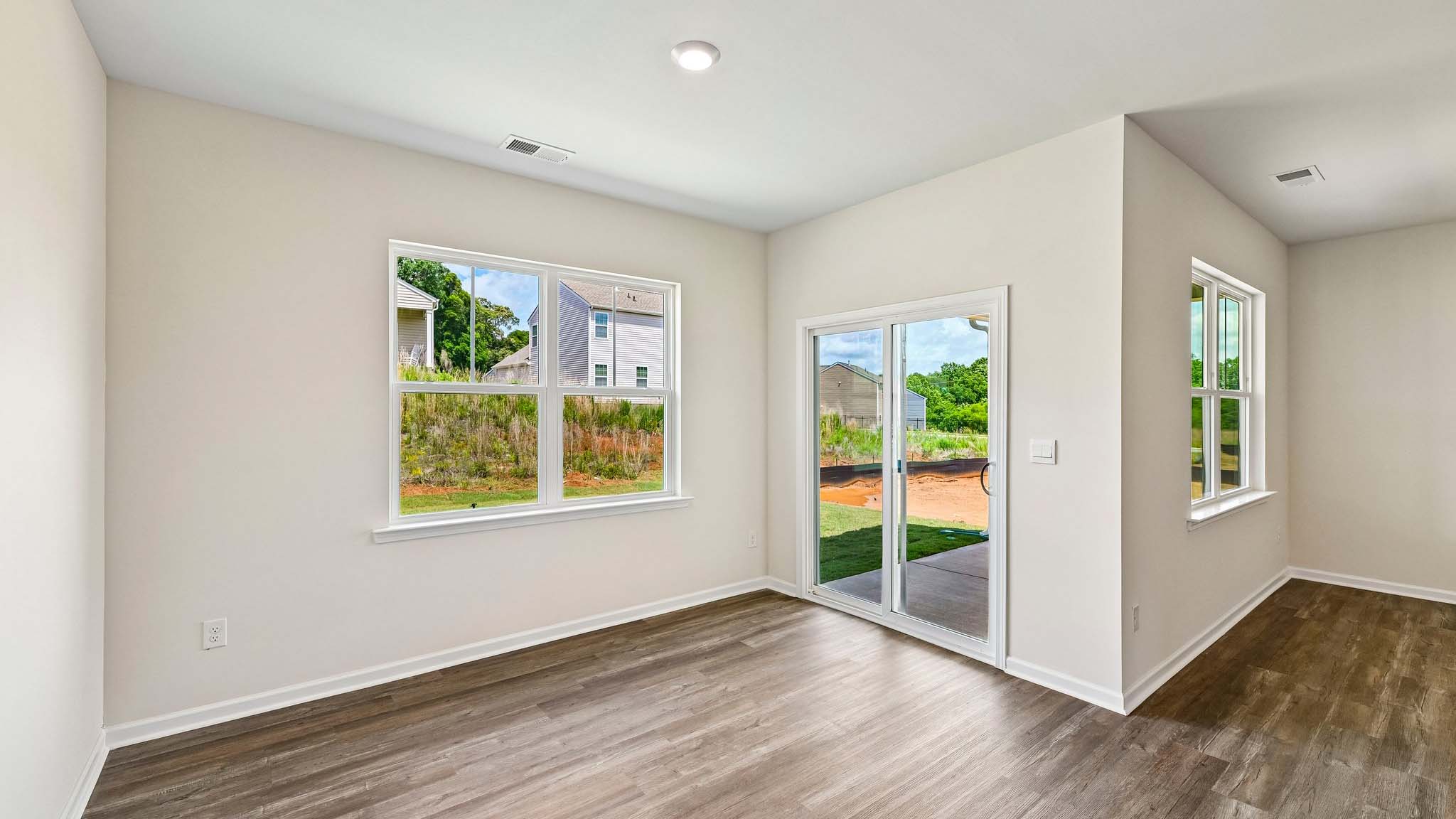 Modern open-concept living room with wood floors, and a fireplace, located beside kitchen