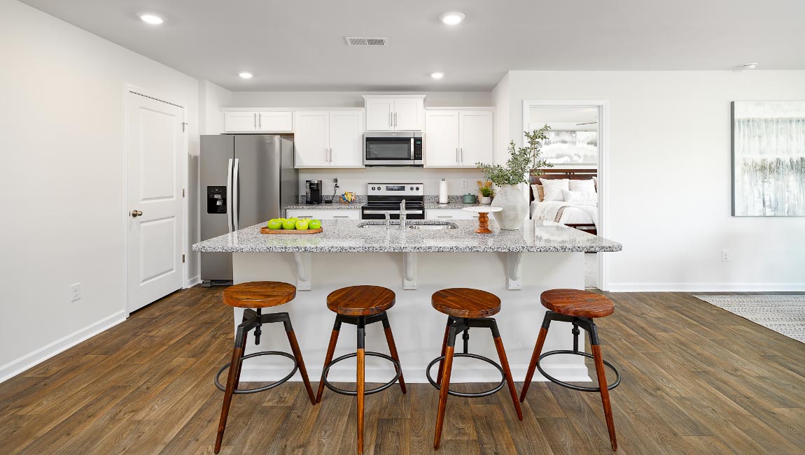 Kitchen and island with white cabinets, quarts countertops, wood floors, and stainless steel appliances