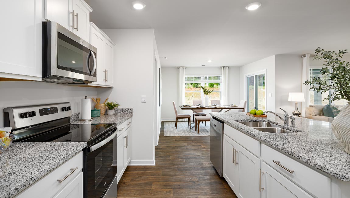 Kitchen and island with white cabinets, quarts countertops, wood floors, and stainless steel appliances
