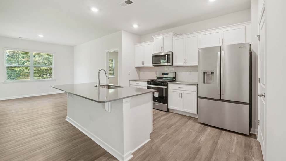 Kitchen and island with white cabinets, quarts countertops, wood floors, and stainless steel appliances
