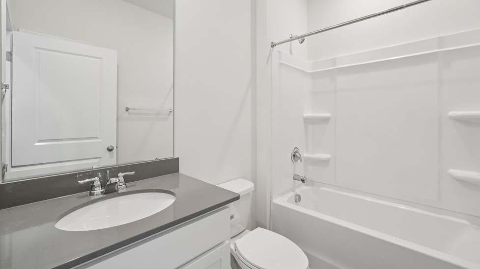 Bathroom with white cabinets and counter, and bathtub
