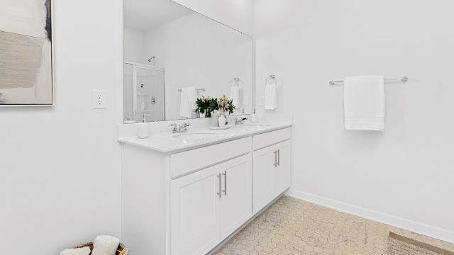 Bathroom with double sinks, white cabinets and counters, and wood floors
