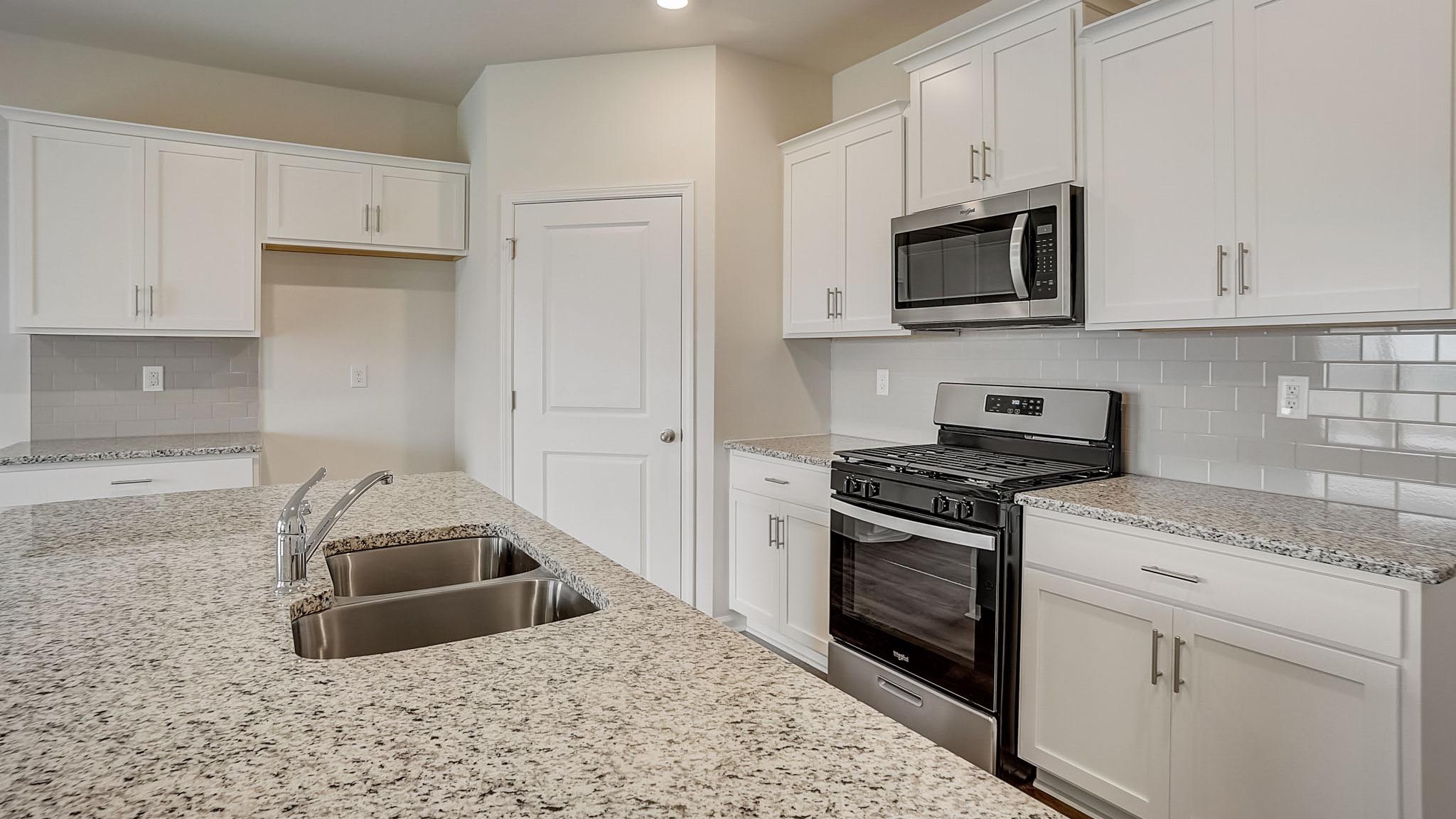 Kitchen and island with white cabinets and subway tiles and stainless steel subway tiles