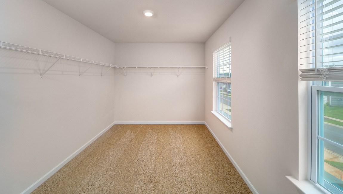 Primary bedroom walk in closet with two windows