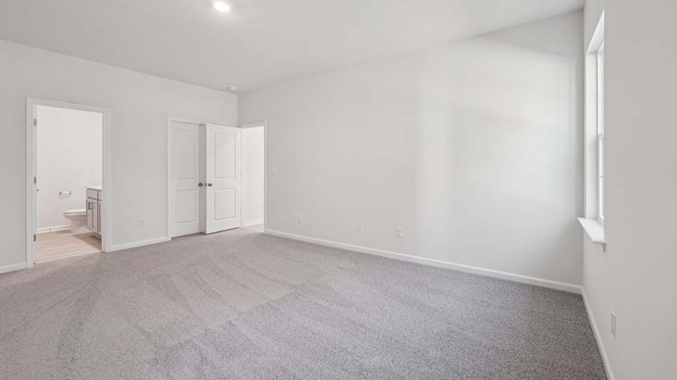 Primary bedroom with carpet and two medium sized windows