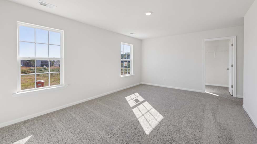 primary bedroom with carpet and large windows
