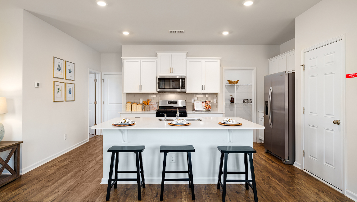 Kitchen and island with white cabinets and wood flooring