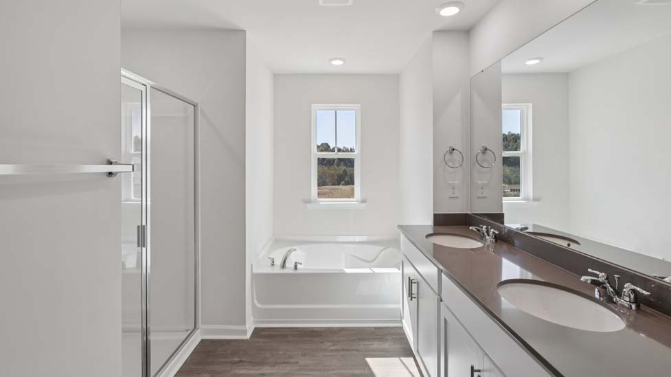 Primary bathroom with double sink vanity, large bathtub, and separate shower