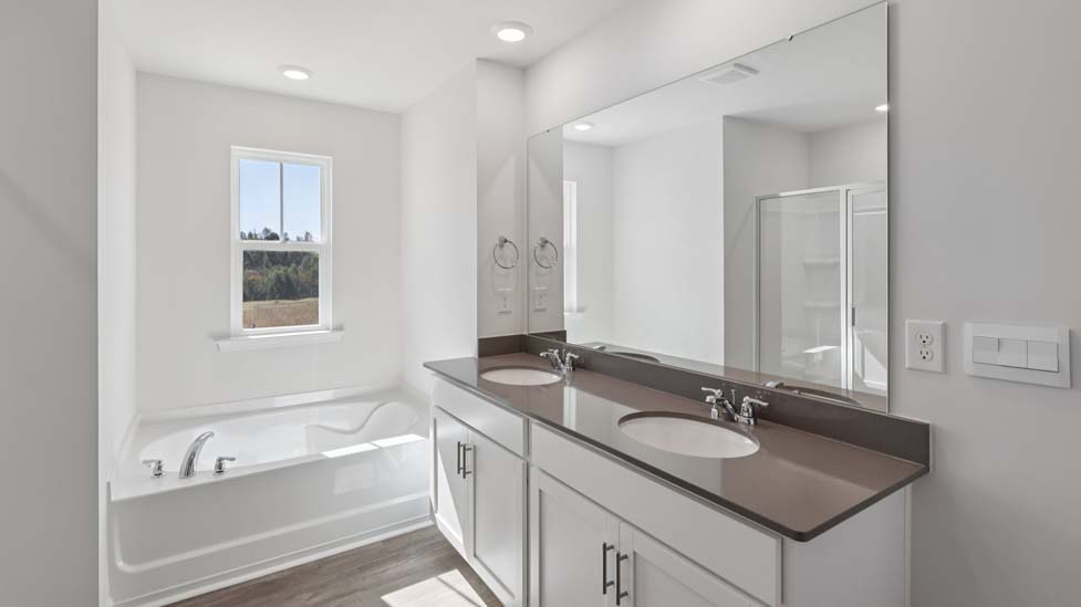Primary bathroom with double sink vanity, large bathtub, and separate shower