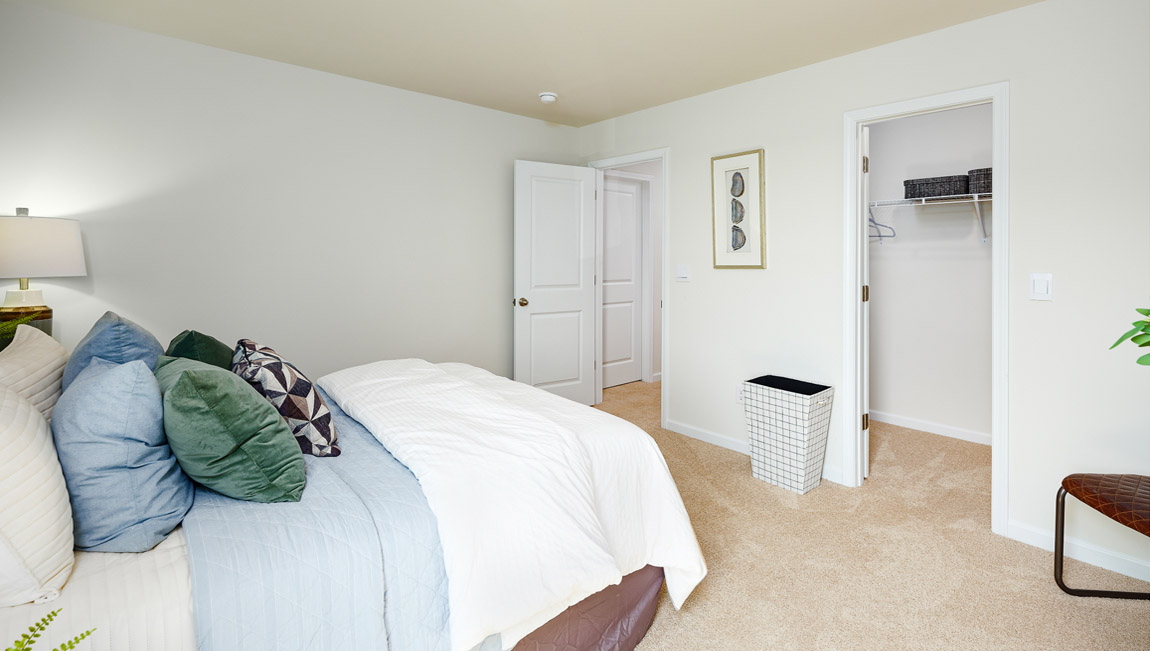 Carpeted bedroom with small window, view of closet