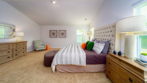 Primary carpeted bedroom with large windows