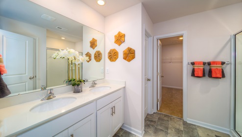 Primary bathroom with white counters and cabinets, double sinks and glass door shower