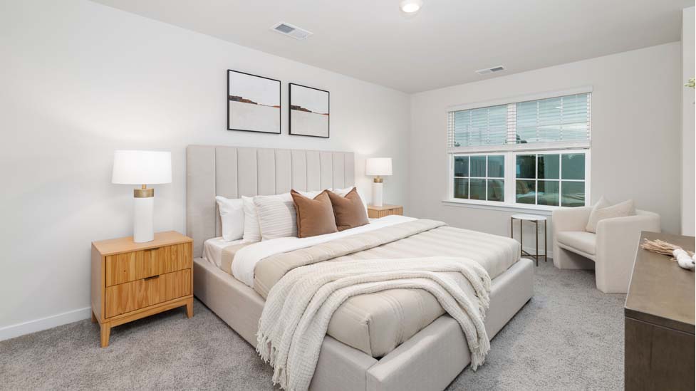Primary bedroom with beige carpet and two large windows