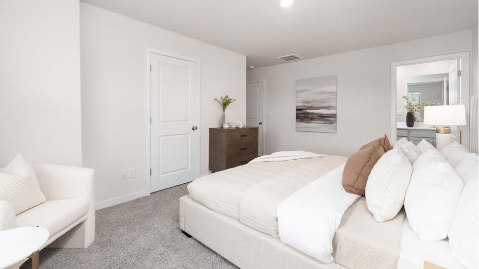 Primary bedroom with beige carpet and two large windows