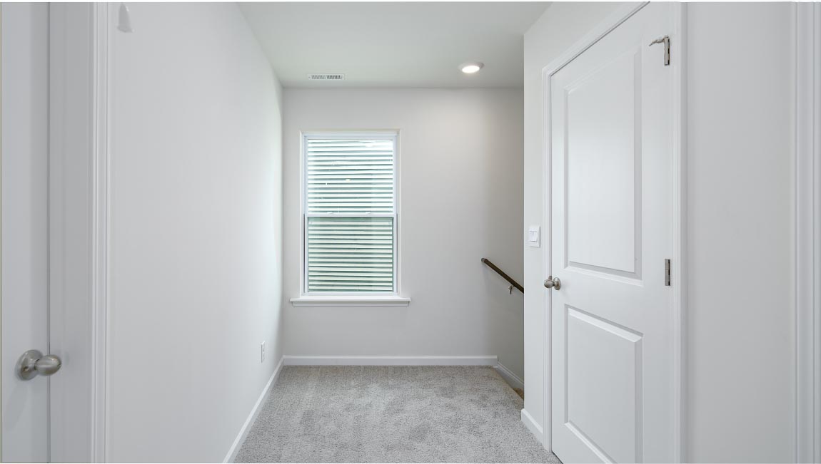 Carpeted bedroom with large window, view of bathroom door