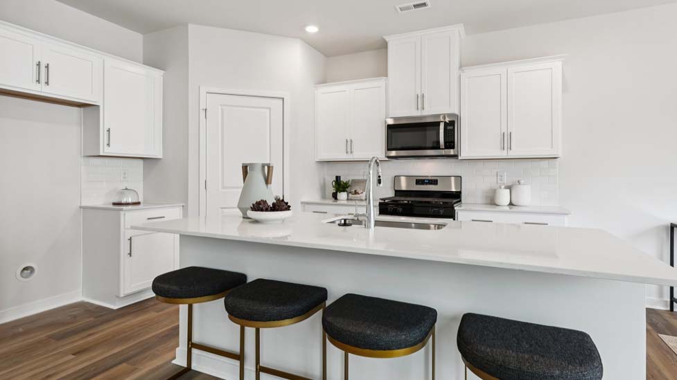 Kitchen and island with white cabinets, quartz counters, wood floors and stainless steel appliances
