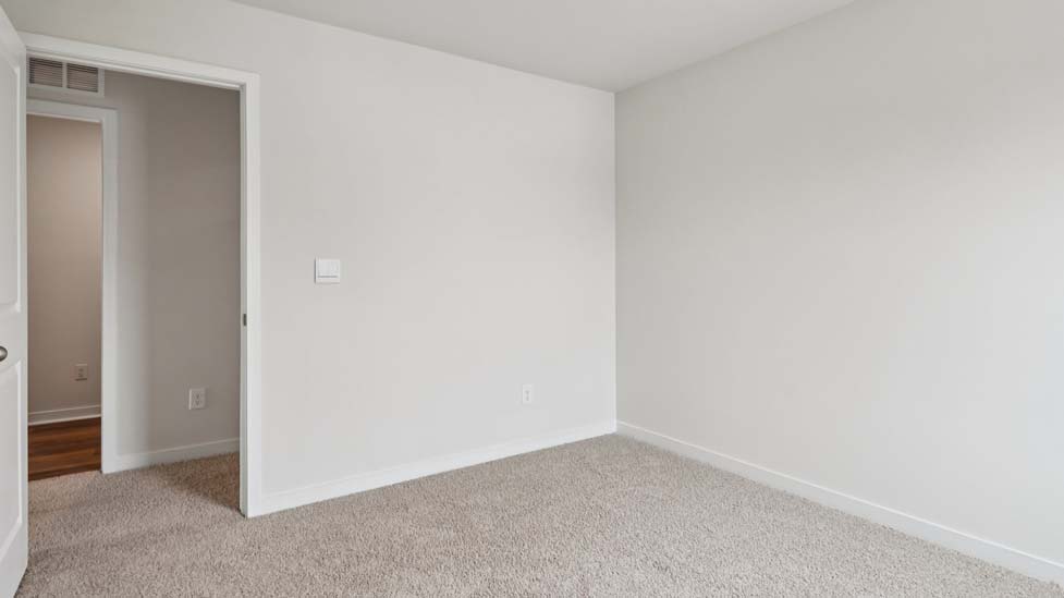 Carpeted bedroom with large window, view of bathroom door