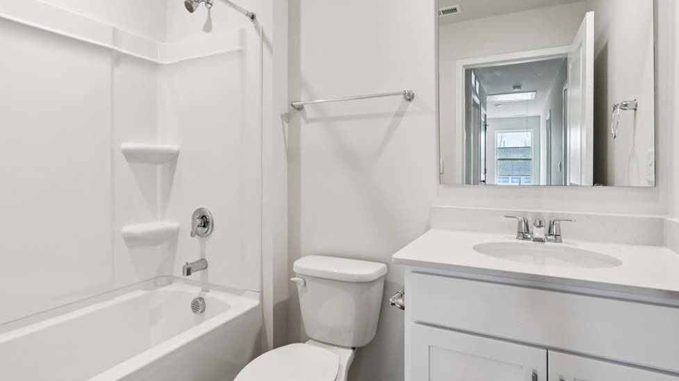 Bathroom with white counters and cabinets, and glass door standing shower