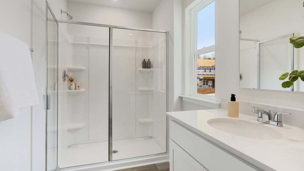Bathroom with white counters and cabinets, and glass door standing shower