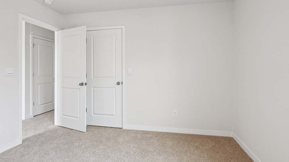 Carpeted bedroom with large window, view of bathroom door