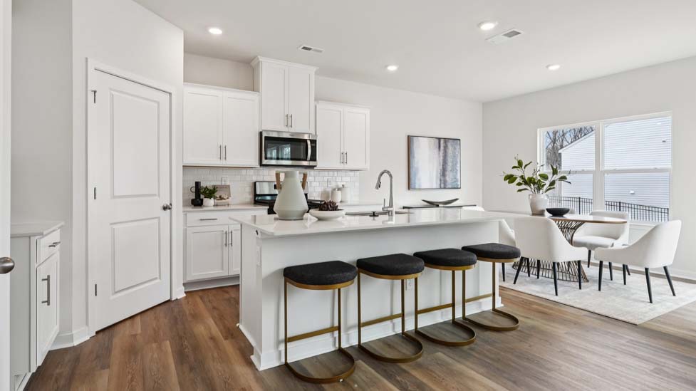 Kitchen and island with white cabinets, quartz counters, wood floors and stainless steel appliances