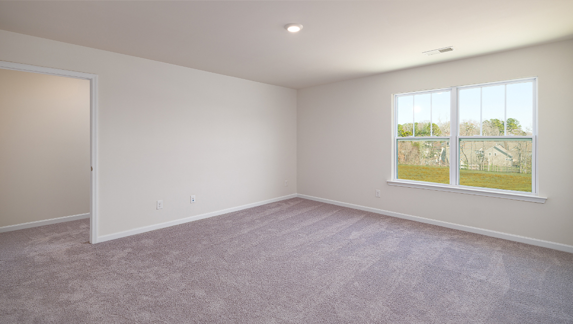 Carpeted bedroom with large window, view of bathroom door