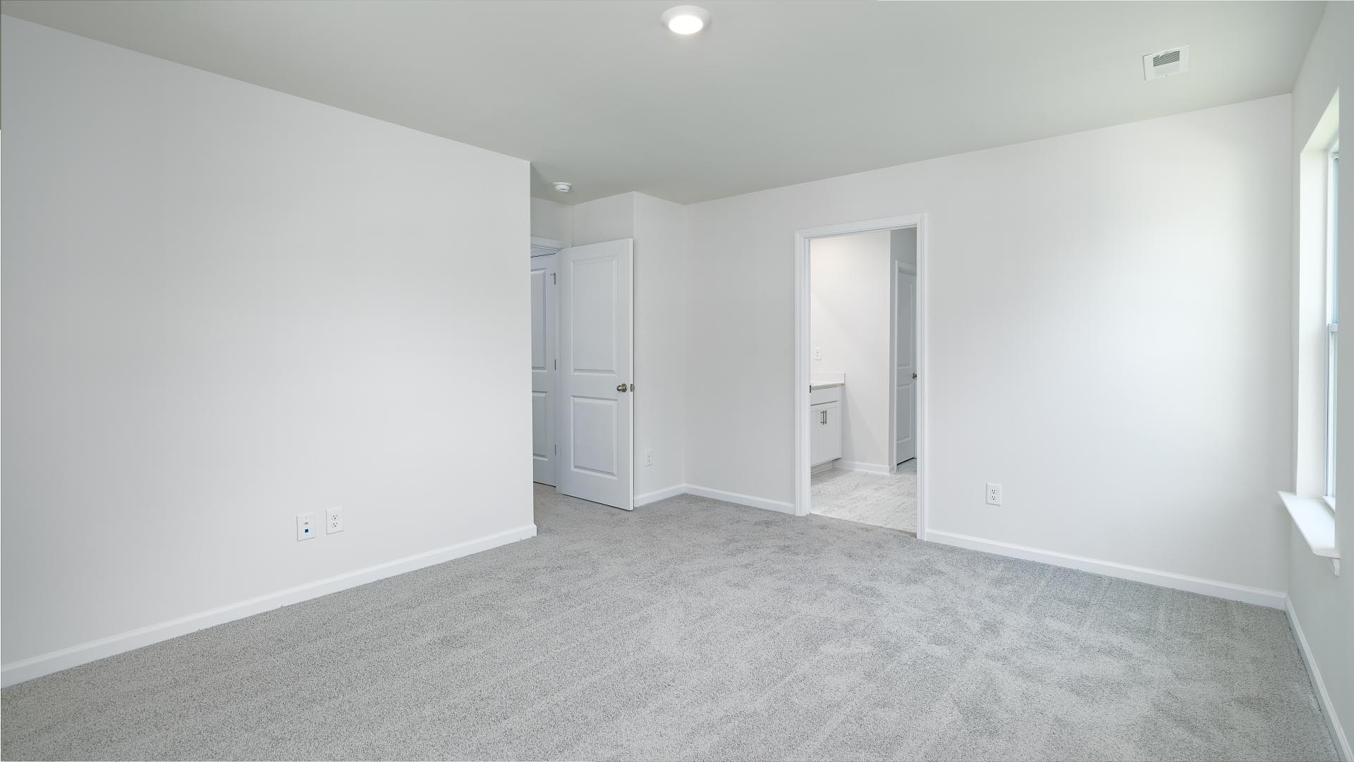Primary bedroom with carpet and two large windows